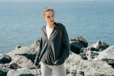 Güneş, mavi denize karşı poz bir siyah ceket emin şık kız koşuya gitti