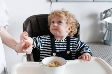 bir sandalye, Anne beslenme yulaf lapası, ailece kahvaltı mutfakta oturmuş kıvırcık küçük oğlu