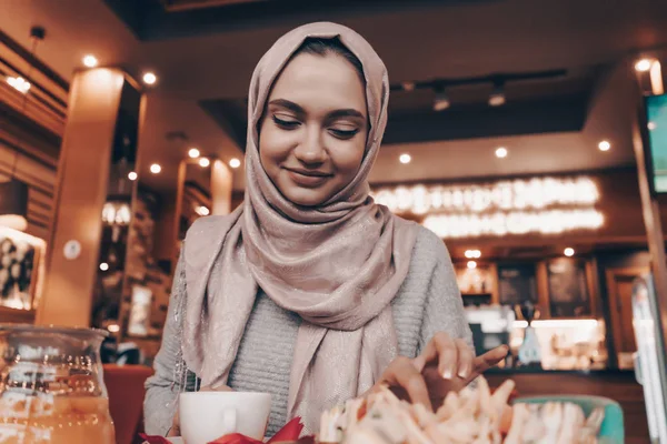 A mosolygós Arab lány hidzsáb ebédelni egy hangulatos, keleti étterem, ízletes ételeket és jó hangulatban — Stock Fotó