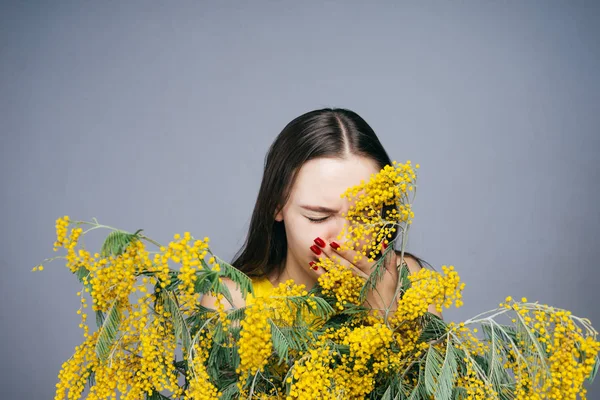 Una joven se para junto a una fragante magnolia amarilla y estornuda, una alergia a las flores — Foto de Stock