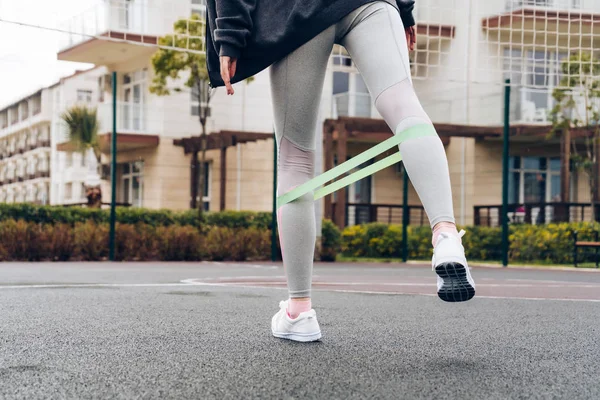 özel bir lastik bant açık havada bacak egzersizleri yapıyor ince atletik kız