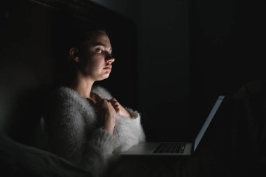 onu laptop korku filmi izlerken yatakta gece geç saatlerde, oturan genç üzgün kız