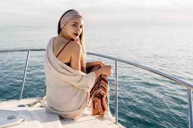 çekici bir kadın şık yaz giysileri Güneş onun beyaz yatta oturur, bir tatil sahiptir