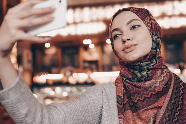Gadis muslim yang cantik melakukan selfie di smartphone-nya, di sebuah restoran — Stok Foto