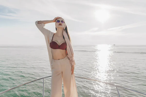 Chica atractiva en ropa de verano elegante posando en su yate al sol, vacaciones en el mar —  Fotos de Stock