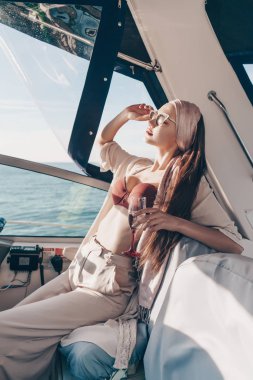 zengin, çekici ve genç bir kadın bir tatil onun yatta sahiptir, şampanya içiyor ve rahatlatır