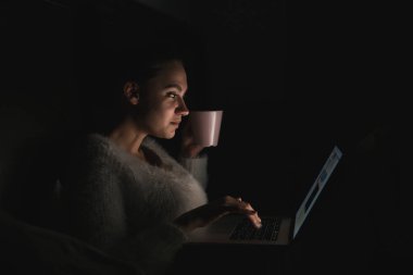 gece geç saatte yatakta otururken, dizüstü bilgisayarda çalışan ve kahve içme kız serbest meslek sahibi genç güzel