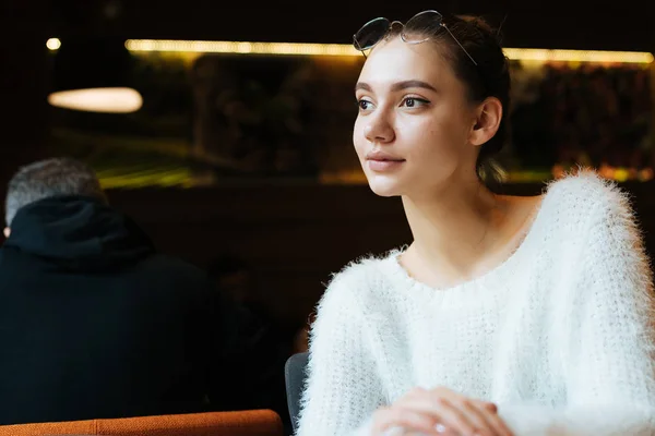 白いセーターで美しい少女学生放課後カフェに座っているし、窓の外に見える — ストック写真