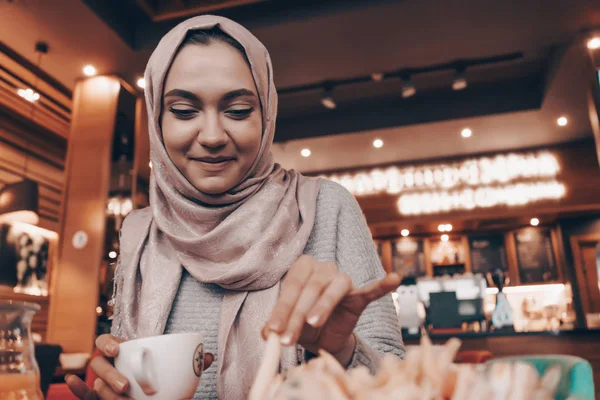 Schöne lächelnde arabische Mädchen im Hijab beim Mittagessen in gemütlichen Café, duftenden Tee trinken — Stockfoto