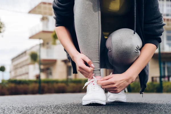 Atletisk ung flicka löpare binder upp skosnören innan jogging utomhus — Stockfoto