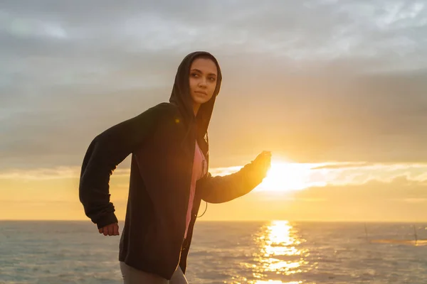 Jovem ativa correndo pelo mar ao pôr do sol, quer perder peso — Fotografia de Stock