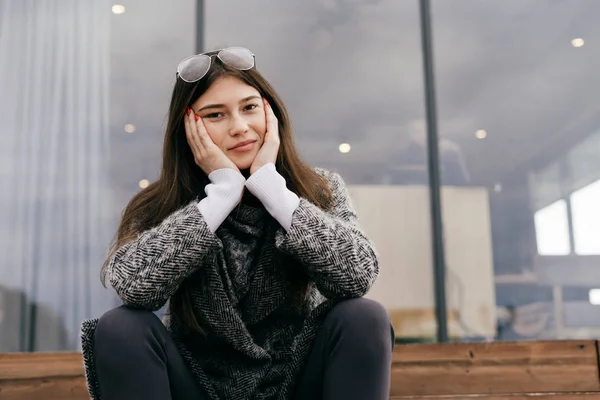 Linda chica morena joven se sienta en las escaleras al aire libre y exhala, estilo calle — Foto de Stock