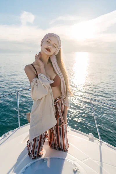 有自信的豪华女孩穿着时髦的衣服, 在游艇上休息, 在阳光下摆姿势 — 图库照片