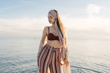 Lüks bir güzel kız bir tatil zevk güneş, onun yatta poz şık yaz giysileri