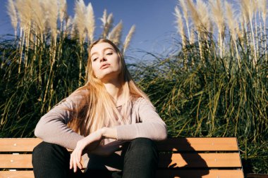 bir ahşap Bank güneşte poz kendine güvenen genç sarışın model kız