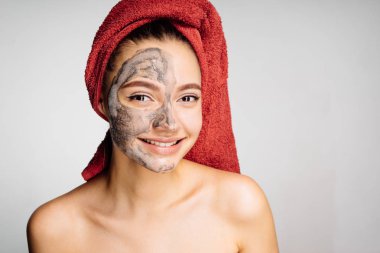 başında kırmızı bir havlu ile güzel genç kız kendini sonra nemlendirici için yüz yarım maskesi olarak görünüyor