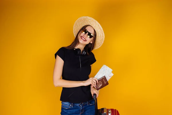 Привлекательная уверенная девушка в соломенной шляпе и солнцезащитных очках отправляется в отпуск, хранит билеты на самолет — стоковое фото