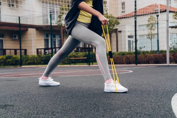 Спортивная стройная девушка выполняет упражнения на ногах на спортивной площадке, хочет похудеть — стоковое фото