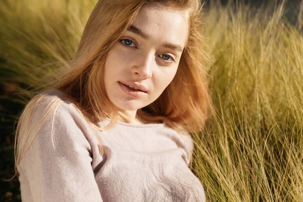 Atraktivní Mladá blondýnka s modrýma očima, pózuje v trávě na slunci — Stock fotografie