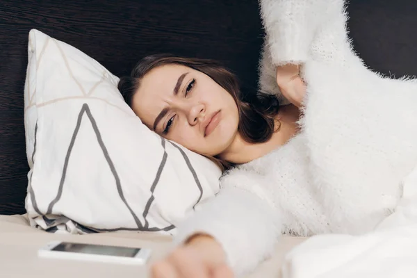 Ein verärgertes junges Mädchen im Schlafanzug wacht früh auf, liegt im Bett und will nicht aufstehen — Stockfoto