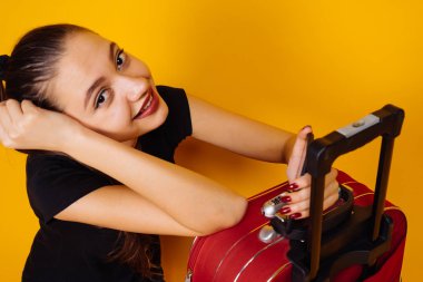 mutlu genç kız siyah T-shirt bir kırmızı çanta yanında oturan gülümsüyor. uzun zamandır beklenen tatil