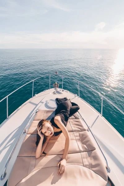 Шикарная сексуальная девушка в черном летнем платье отдыхает на своей яхте на солнце, наслаждается отпуском — стоковое фото