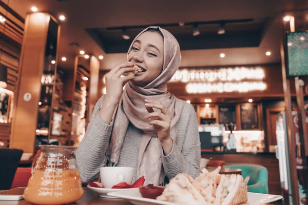 Vicces Arab lány hidzsáb egy hangulatos étterem ízletes ételt — Stock Fotó