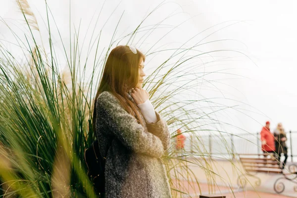Pensive young brunette girl in trendy gray coat posing outdoors — Stock Photo, Image