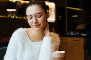 güzel güzel kız öğrenci bir beyaz kazaklı ve Üniversitesi'nde okuyan sonra gözlük oturur bir kafede içecekler latte