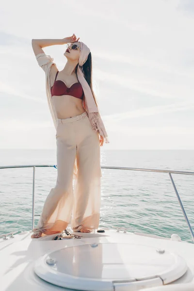 Atraktivní dívka v stylových letních šatech pózuje na jachtě na slunci, těší námořní plavba — Stock fotografie