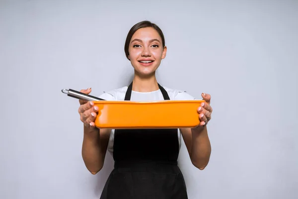 Красива молода дівчина шеф-кухар в чорному фартусі запечений смачний пиріг в духовці, посміхаючись — стокове фото