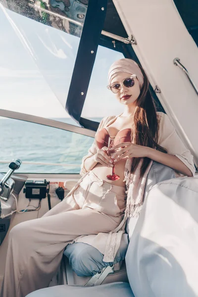 Confident beautiful girl in sunglasses swims on her yacht, drinks champagne and enjoys a rich life — Stock Photo, Image