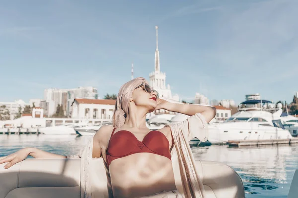 Sexy mujer joven en gafas de sol y traje de baño rojo descansando y relajándose en un yate, navegando a las islas de vacaciones —  Fotos de Stock