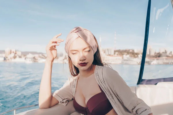 Uma jovem de luxo com um lenço na cabeça repousa em seu iate, velas no mar das Caraíbas, poses — Fotografia de Stock