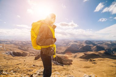 Doğa ve güneşin sıcak bir ceket ve sarı bir sırt çantası, Dağları, seyahatleri ile genç bir kız seviyor