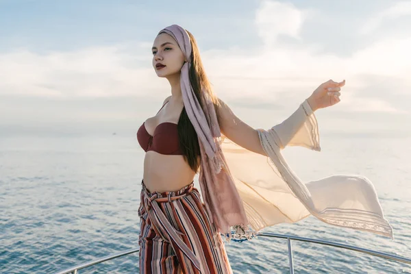 Lujosa chica elegante en ropa de verano posando contra el mar, disfrutando de unas vacaciones —  Fotos de Stock