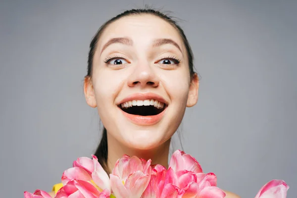 Gelukkig jong meisje poseren en kijken naar de camera, houden een boeket van roze bloemen — Stockfoto