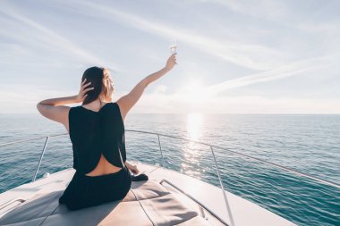 siyah elbiseli bir genç zengin kadın bir tatil onun yat, Karayip Denizi sahiptir.