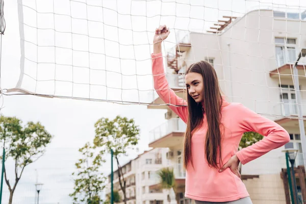 Giovane ragazza sicura di sé con i capelli lunghi in posa sul campo sportivo, giocare a pallavolo — Foto Stock