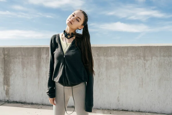Приваблива впевнена дівчина в чорному стильному одязі позує на сонці, перед тренуванням — стокове фото