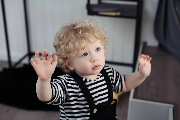 Lindo niño rizado con ojos azules de pie en la habitación — Foto de Stock