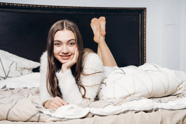 Schönes charmantes Mädchen im Schlafanzug liegt abends im Bett, ruht sich nach einem harten Arbeitstag aus und lächelt — Stockfoto