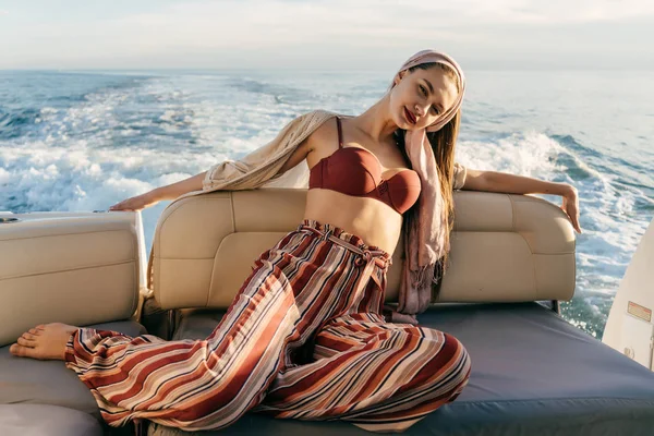 Buena chica en pantalones elegantes se encuentra en el barco, posa y disfruta de una rica vida y vacaciones —  Fotos de Stock