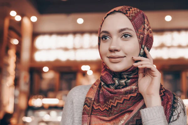 Attractive young muslim girl with headscarf on her head posing and smiling, sitting in a restaurant — Stock Photo, Image