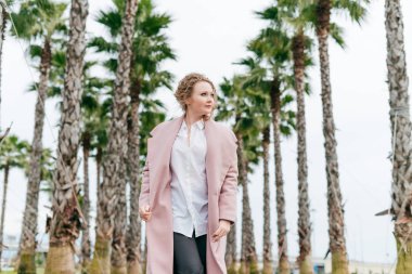 pembe bir ceket güzel şık kadın bahar yeşil park üzerinden yürür, sıcaklık sahiptir