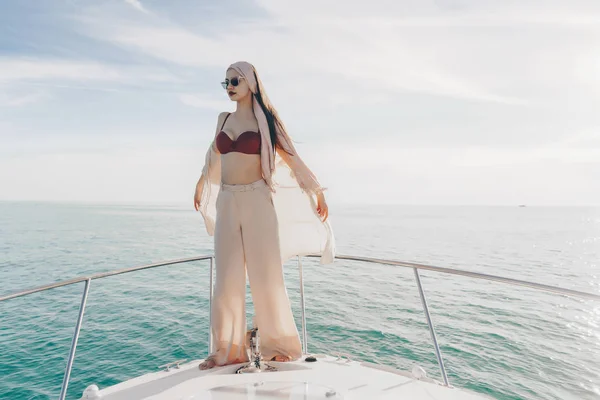 Lujosa chica con estilo disfruta de viaje por el mar en un yate, al sol, posa y descansa —  Fotos de Stock