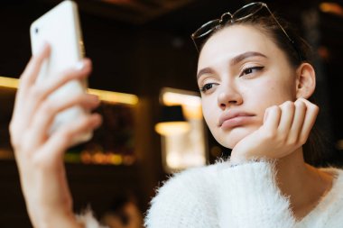bir kafede oturuyor ve onun smartphone bakarak yorgun üzgün kız sıkılmış