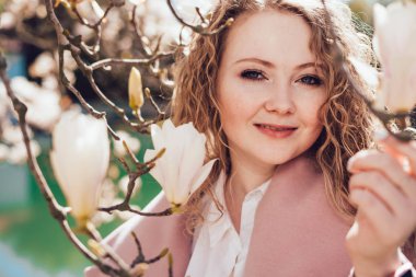 çiçek açan magnolia, yanındaki parkta poz kıvırcık güzel kadın gülümseyerek