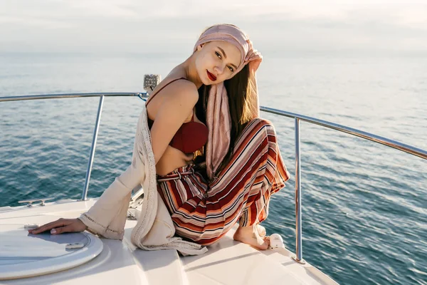 Chica con estilo de confianza en la ropa de verano se sienta en un barco y mira a la cámara, navega en el mar Caribe —  Fotos de Stock