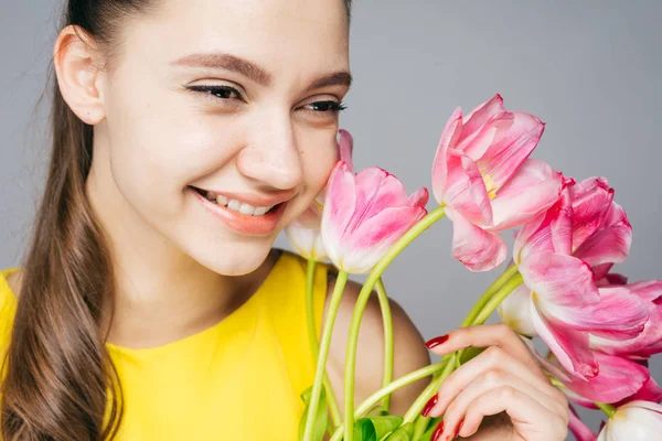 Красивая улыбающаяся девушка в желтом платье радуется весной, держит букет ароматных розовых цветов — стоковое фото